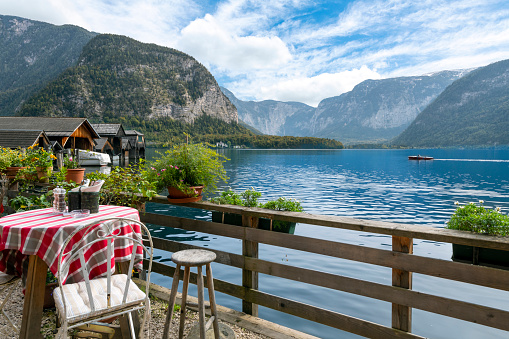 A small table at an outdoor cafe overlooks the lake and Alps in the mountain town of Hallstatt, Austria.