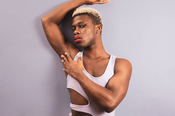 istock An african young man posing on a purple background, androgynous man concept. 1434803568