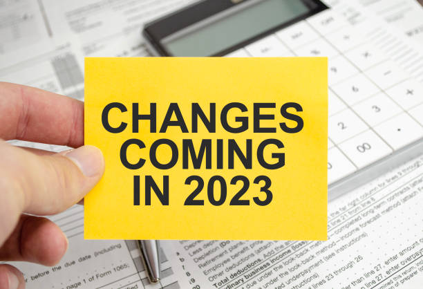 notepad with text Changes Coming in 2023 with calculator and tax forms stock photo