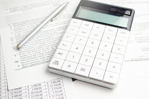 pen, calculator and tax forms concept on white background