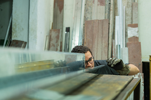 Latino man with an average age of 20 dressed casually Employees of a locksmith are working together cutting metal material