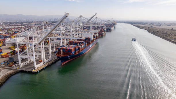 Aerial stock photos of large scale commercial shipping cargo container ships moored in Oakland alongside Alameda California.