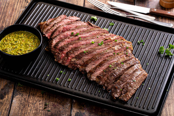 Grilled flank steak with chimichurri sauce on a grill pan Grilled flank steak with chimichurri sauce on a grill pan on wooden table marinade stock pictures, royalty-free photos & images