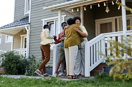 Full length portrait of happy black family embracing on porch of new house, copy space