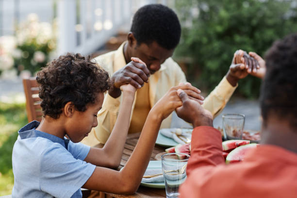 Boy Praying With Family at Dinner