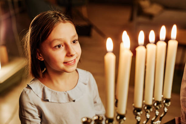istock Young Girl Looking at Menorah Candle 1434820317