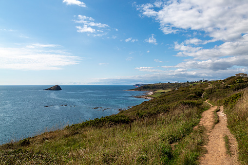 Looking along a coastal footpath besides Wembury Bay with a view of The Great Mew Stone in the ocean