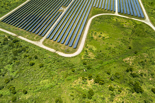Aerial view of sustainable electrical power plant between agricultural farmlands with photovoltaic panels for producing clean electric energy. Concept of renewable electricity with zero emission.