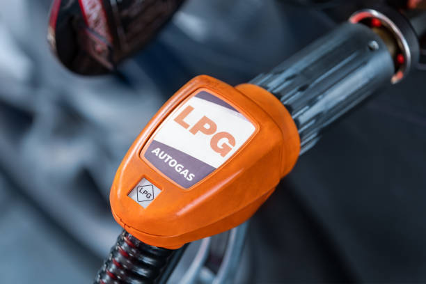 Close-up detail view of fuel autogas pump gun connected with noozle adapter to car tank to refill at car gas filling station. Refueling vehicle with liquefied lpg or lng product. Safety technology stock photo