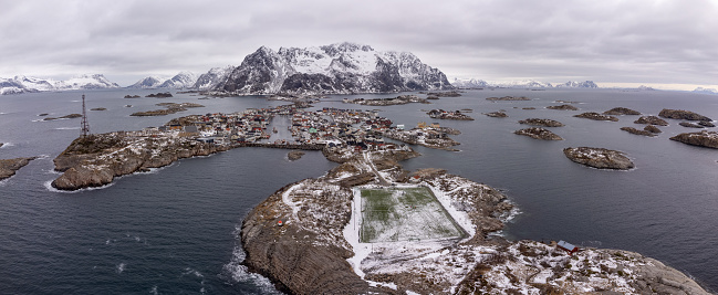 Aerial snowy winter view of the small fishing town of Henninsvaer in the Lofoten Islands of Northern Norway with it's famous synthetic football pitch