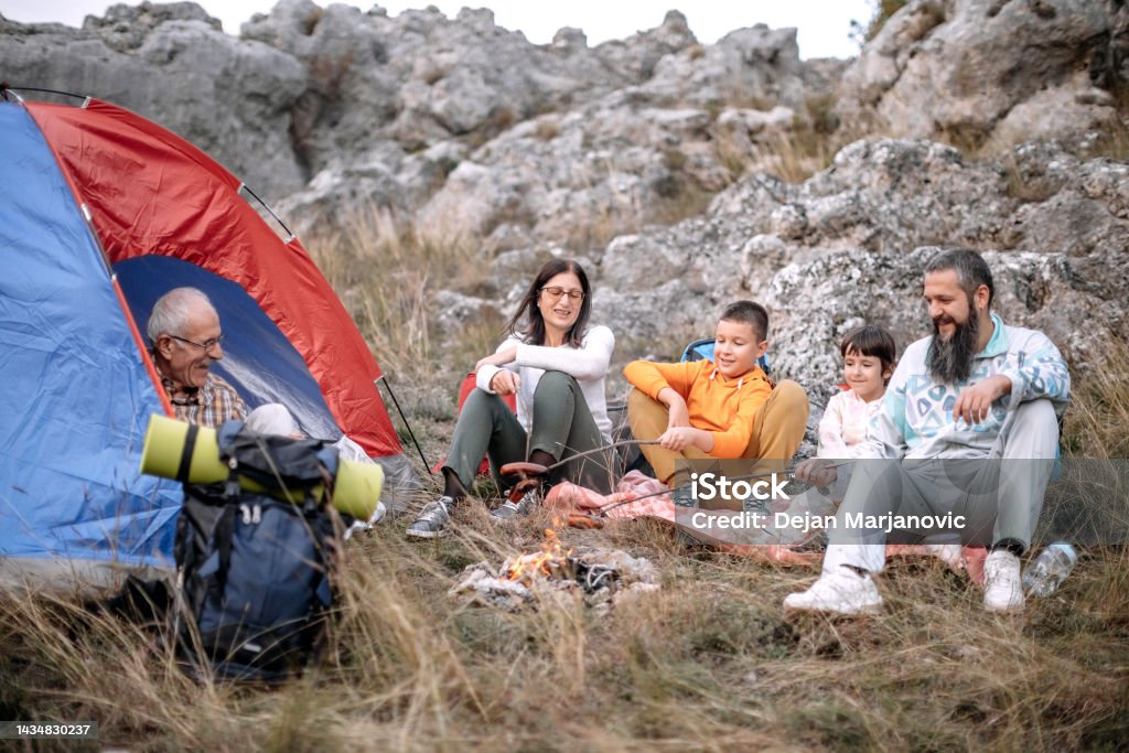 Family enjoying in nature preparing sausage on campfire Multi-generation family camping on the mountain 10-11 Years Stock Photo