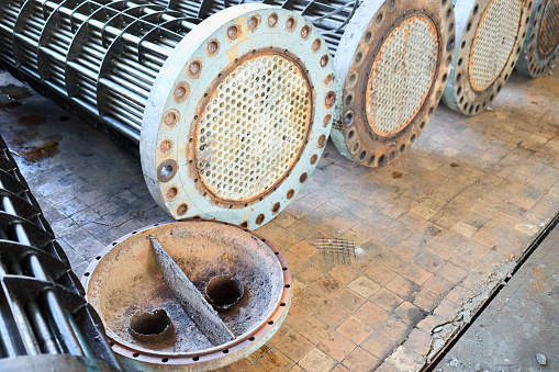 Corrosion, refinery heat exchangers chiller tubes with flange system. Row of industrial heat exchangers or boiler with covers rusty tube sheet or tube board, with deposits and corrosion.