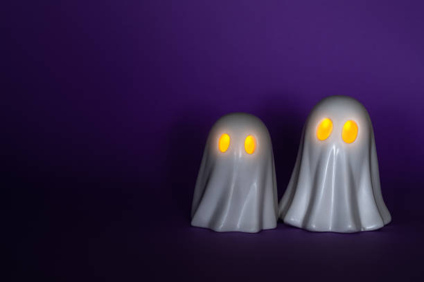 Two funny White Ghosts Halloween decor with glowing eyes on a purple background.