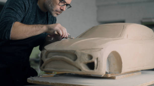 istock Car designer works on the model of car using shaping tools to smooth out bonnet 1434837192