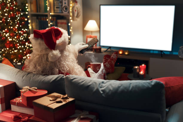 Santa Claus watching television at home stock photo