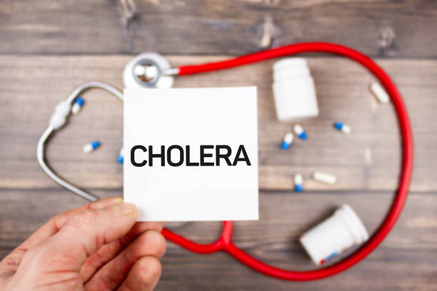 콜레라 - 손에 텍스트. 테이블에 청진기와 의약품의 배경에 콜레라 진단. - cholera bacterium 뉴스 사진 이미지