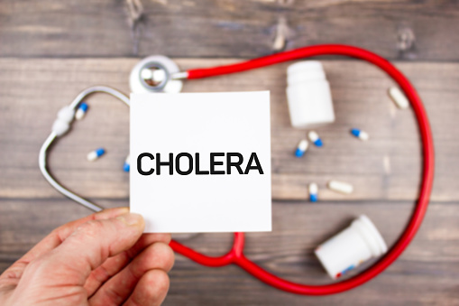 The CHOLERA - text in hand. CHOLERA diagnosis on the background of a stethoscope and medicines on the table.