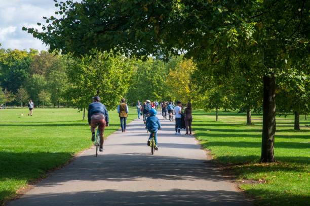люди, идущие пешком и на велосипеде в кенсингтонских садах - kensington gardens стоковые фото и изображения