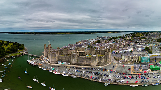 CAERNARFON, UK - AUGUST 31 2022: Aerial view of the ancient Caernarfon Castle in North Wales.  The castle is currently undergoing repair work and was used for the investiture of Prince's of Wales.