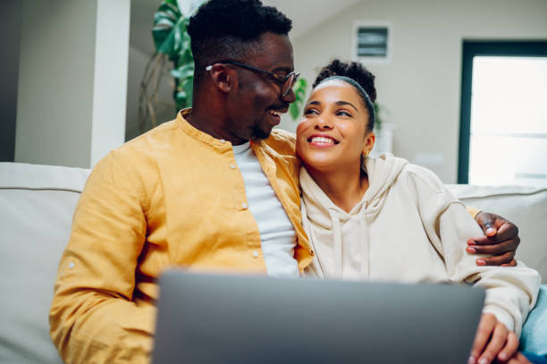 istock Multiracial couple using laptop while sitting on a sofa at home 1434849148