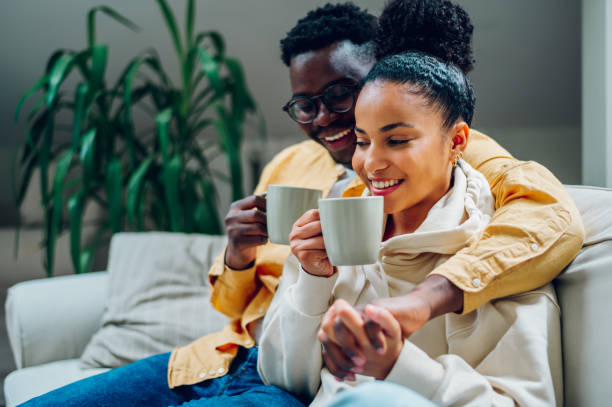 istock Multiracial couple relaxing on a couch at home and drinking coffee 1434849157