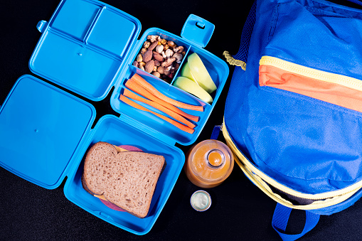 Close up photo of student lunchbox on black background. No people are seen in frame. Shot with a full frame mirrorless camera.