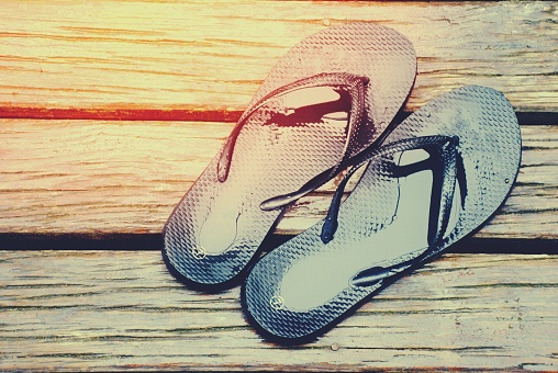 A pair of Jandas/ Sandals or Flip Flops on wooden decking after the rain.