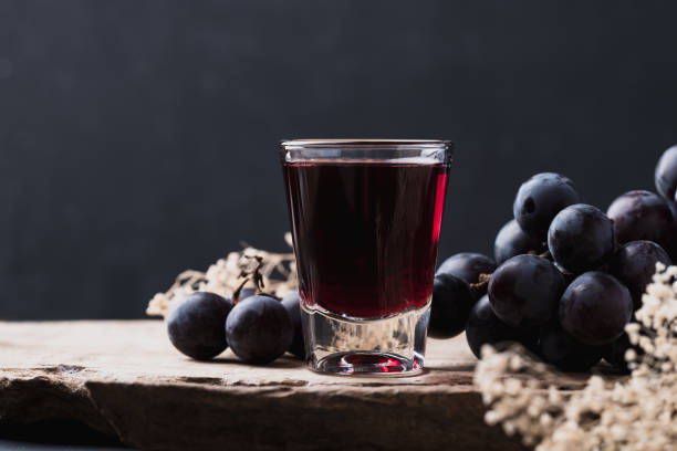 Black grape juice in glass on wooden with black background stock photo