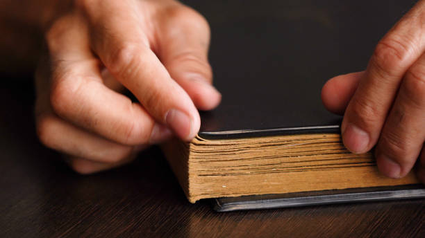 istock A man's hand and an old book on the table 1434866817