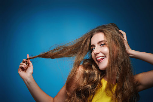 happy woman with strong healthy curly hair dancing on blue background