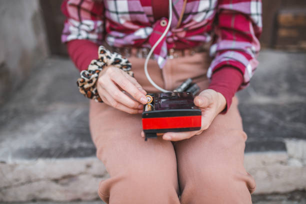 Young woman woman dressed in a plaid shirt enjoying listening to music on an old fashioned, retro Walkman