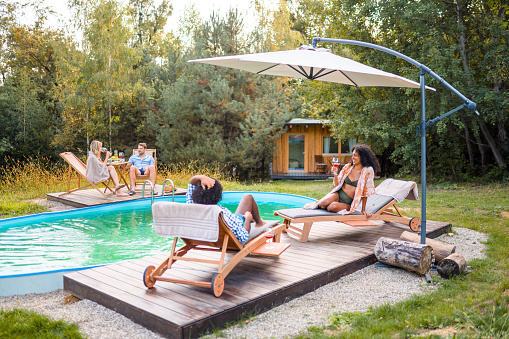 Mixed race couples spending their quality time and relaxing by the swimming pool in Boutique Glamping Divja DiVine in Slovenia.