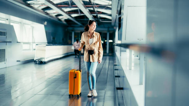 terminal dell'aeroporto internazionale. bella donna asiatica con bagagli e camminando in aeroporto - beautiful airport women one person foto e immagini stock
