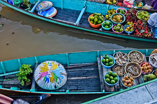 Market traders selling colorful fruit, drinks and food at the floating market using wooden boats