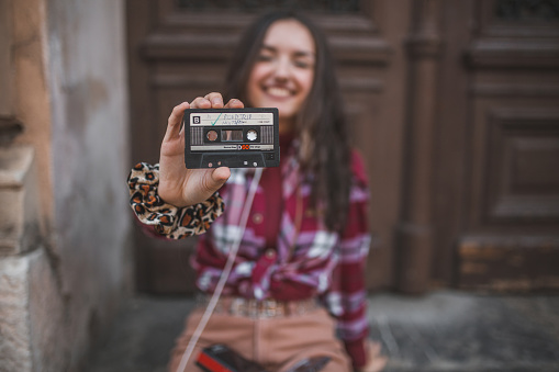 Young woman woman dressed in a plaid shirt enjoying listening to music on an old fashioned, retro Walkman
