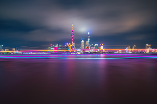 Shanghai skyline at night, showing the Huangpu river with passing cargo ships, and financial district