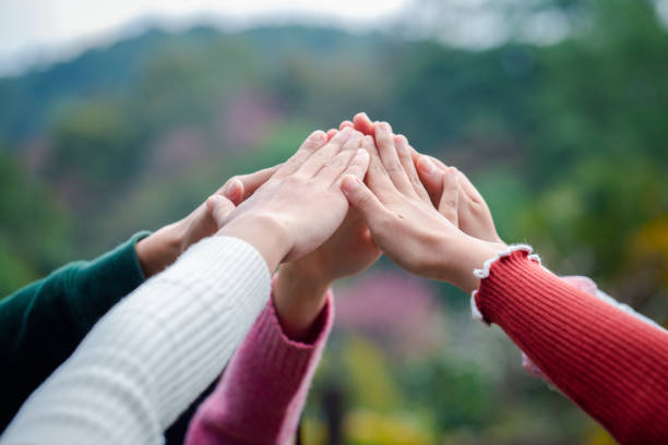 A diverse group of people connects their hands as a supportive sign expressing a sense of teamwork. Unity and togetherness.