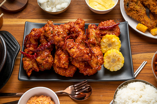 Korean fried chicken with spicy sauce  traditional Korean food, Fried chicken with sweetcorn and Kimchi pickle on wooden table.