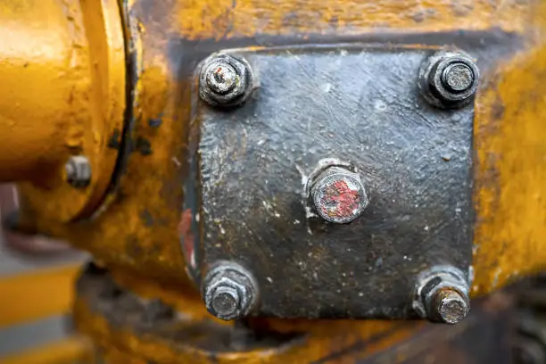 Photo of Metal hatche plate of compressor for revision close-up painted with yellow paint bolted with studs and nuts background copy space.