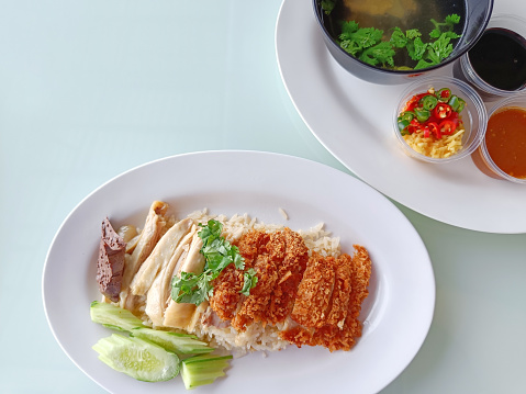 steamed rice topped with boiled chicken Mixed with Fried Chicken Served with broth and dipping sauce, top view. The most popular street food in Thailand is called Khao Mun Gai.