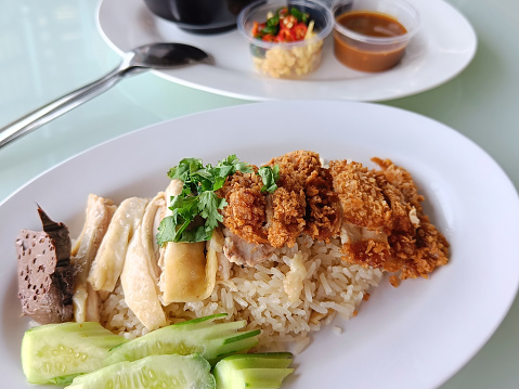 steamed rice topped with boiled chicken Mixed with Fried Chicken Served with broth and dipping sauce, side view. The most popular street food in Thailand is called Khao Mun Gai.