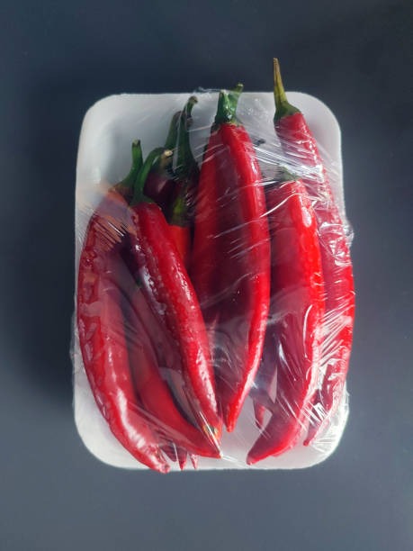 Packaged and labeled red chili peppers on an isolated gray background