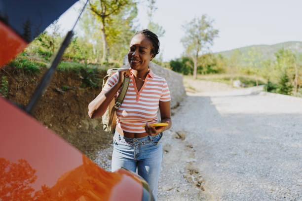 istock Young woman using maps on mobile phone while on a road trip 1434898939