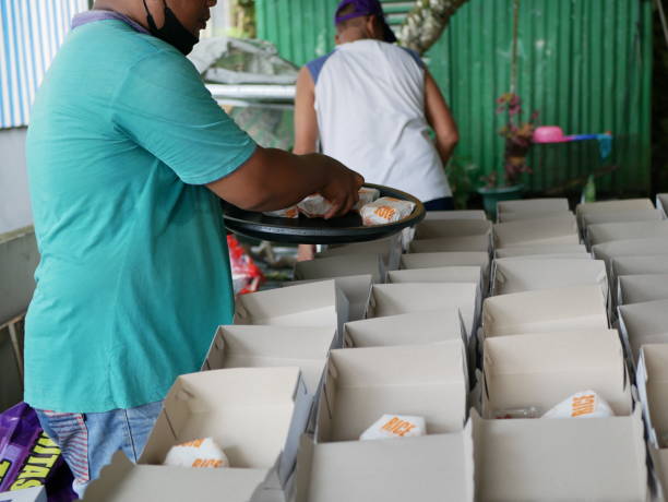 Tarakan, Indonesia: Apr 25,2021: Small group of people working in charitable foundation. Small group  of Indonesian people packing food in the paper box fo donation. stock photo