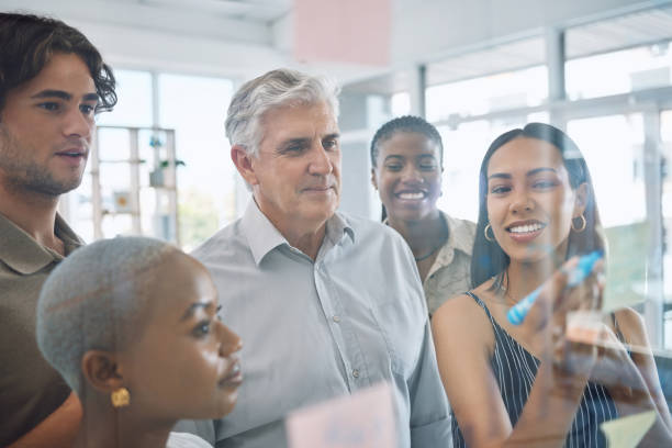 istock Teamwork solution, planning strategy ideas and employee collaboration in learning, meeting and vision on glass wall in creative agency. Diversity, business people and designers working schedule notes 1434900512