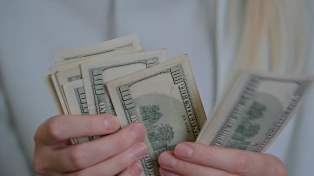 Close-up of female hands holding paper dollar banknotes.
