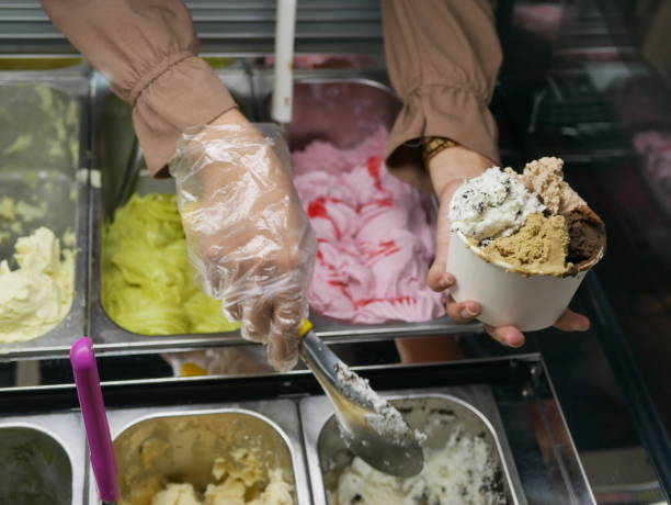 an Indonesian waitress in ice cream shop serving cold ice cream in cup to customer. an Indonesian waitress serving ice cream in cup. stock photo