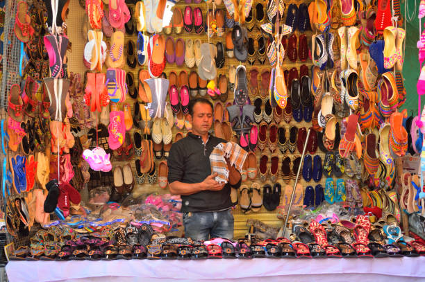 мужчина, продающий самую разнообразную обувь и сандалии в придорожном ларьке на окраине пушкар мела. - camel fair стоковые фото и изображения