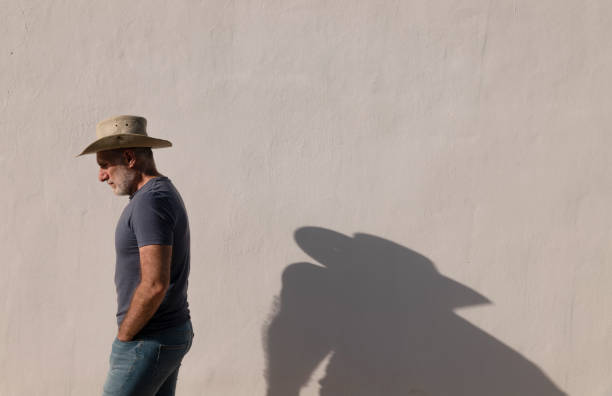 ritratto di uomo adulto in cappello da cowboy contro la parete bianca con la luce del sole e l'ombra - the western wall foto e immagini stock