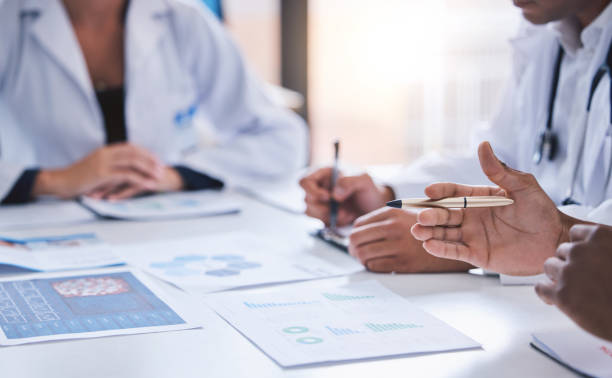 team, medical analysts and doctors consulting with paperwork of graphs, data and charts in hospital conference room. closeup of healthcare staff discussing statistics, results and innovation strategy - smiling research science and technology clothing imagens e fotografias de stock